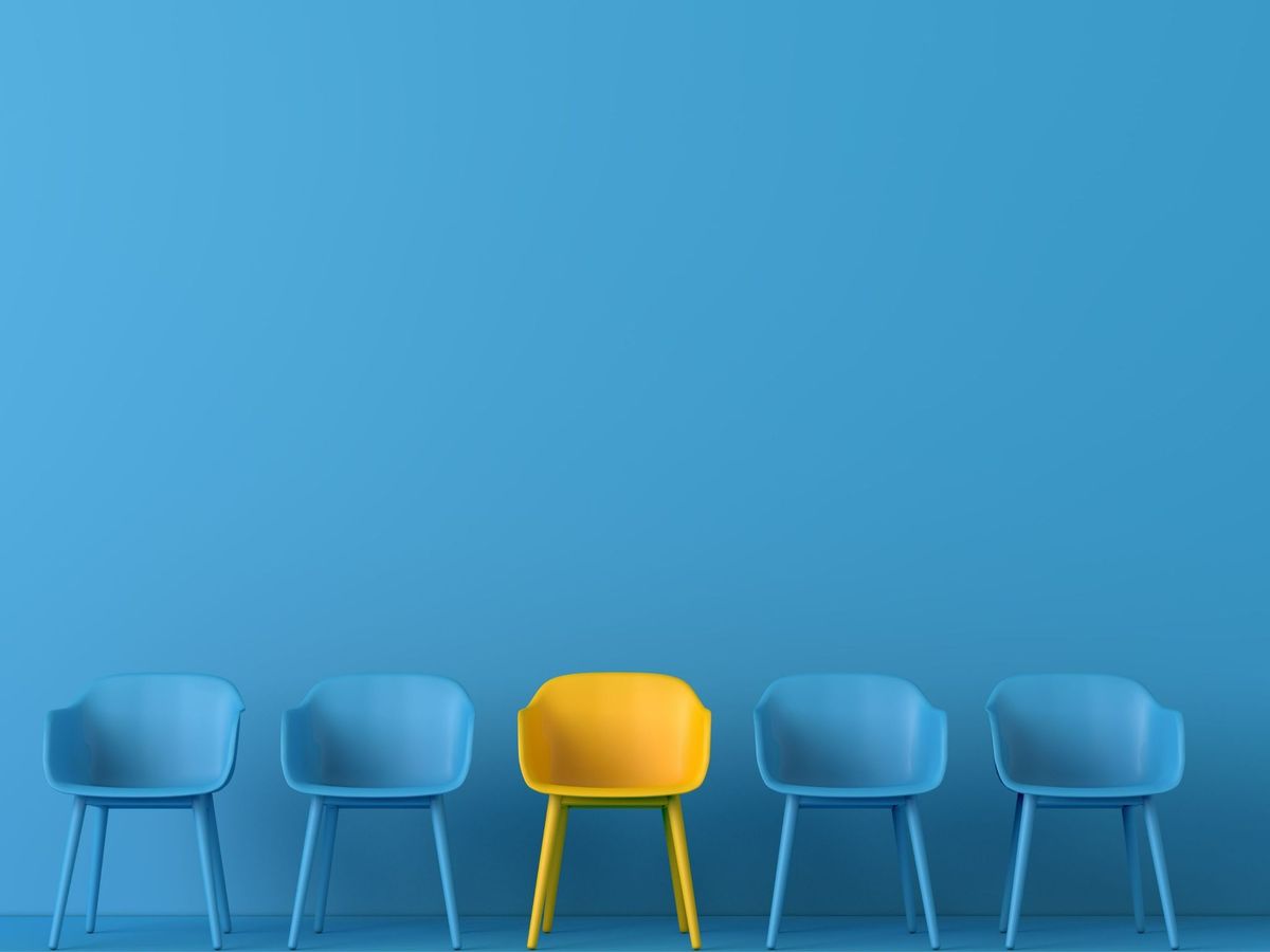 One yellow chair standing out among four identical blue chairs against a blue background