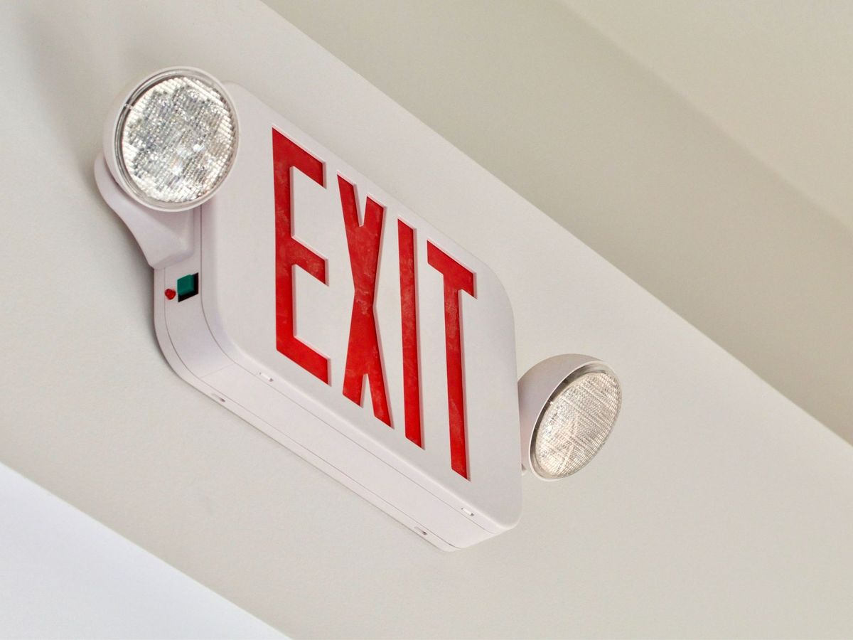 Red exit sign with emergency lights mounted on a ceiling