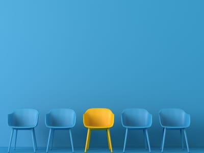 One yellow chair standing out among four identical blue chairs against a blue background