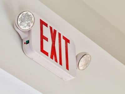 Red exit sign with emergency lights mounted on a ceiling